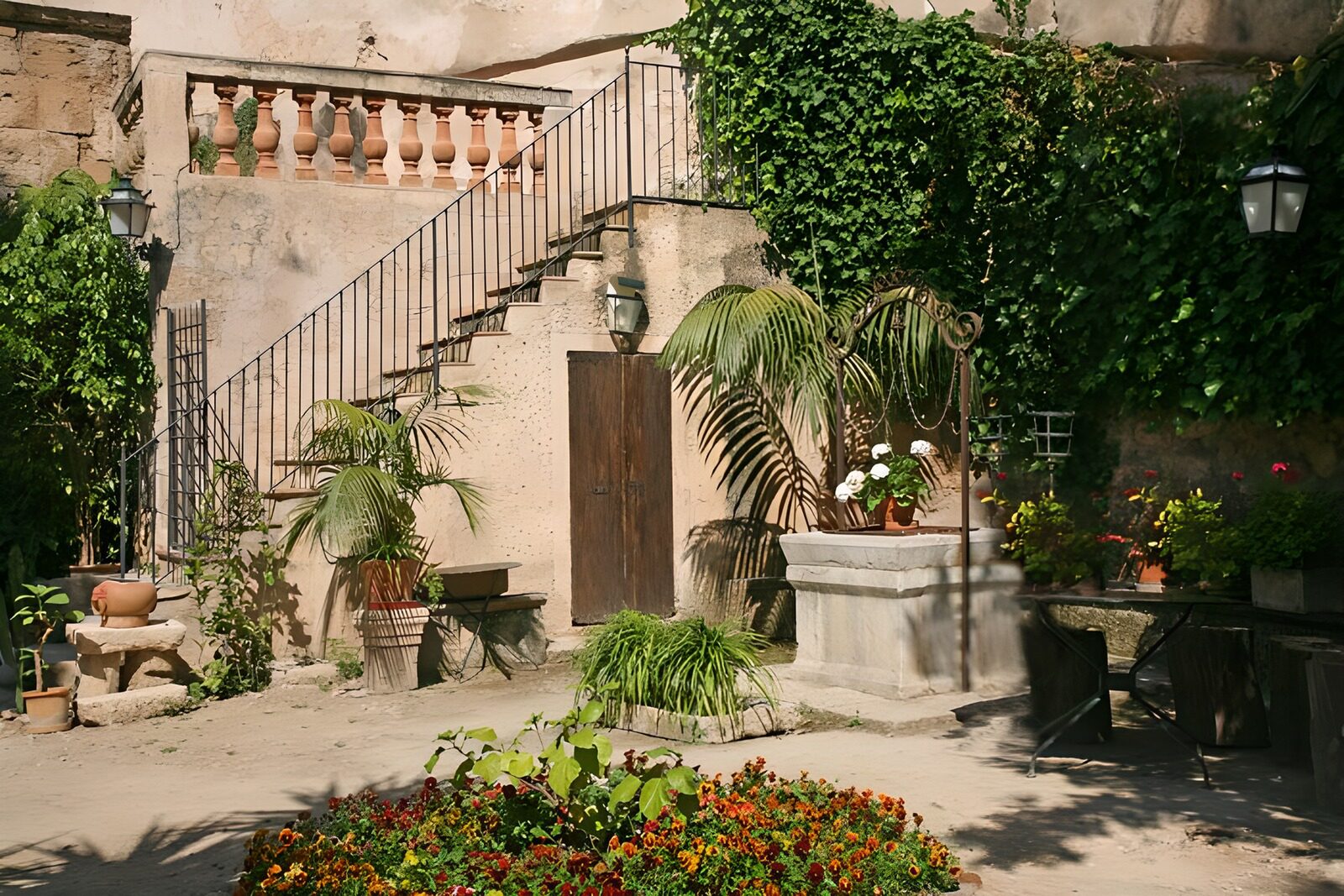 PDGIT7015173: Cortile al sole con fiori e pozzo
