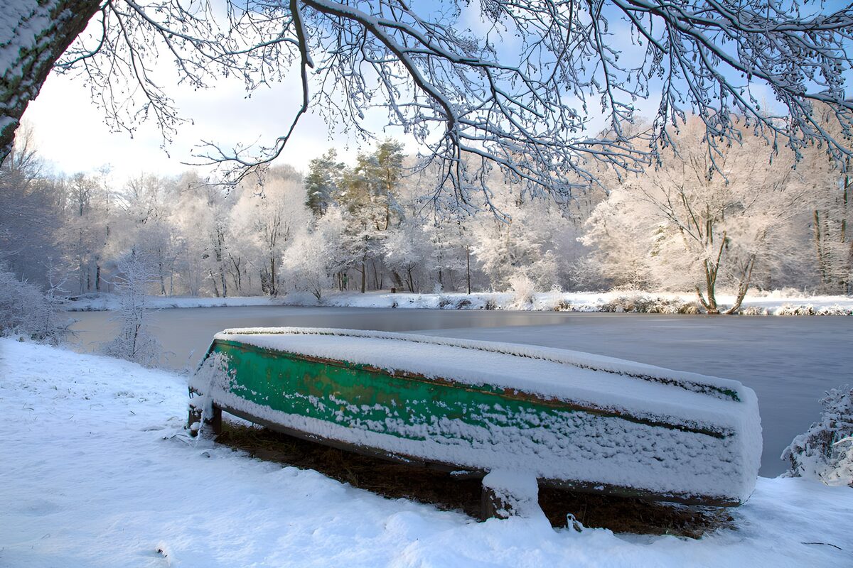 PDGIT6694294: Barca verde capovolta sulla riva innevata