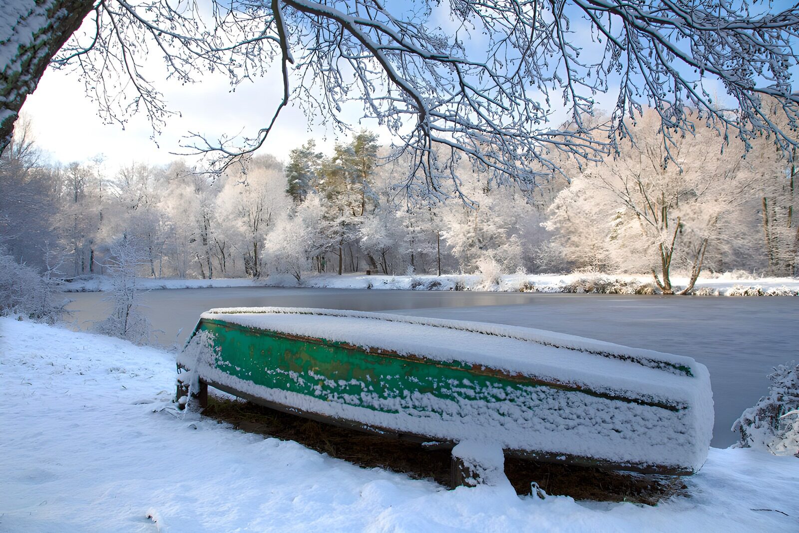PDGIT6694294: Barca verde capovolta sulla riva innevata