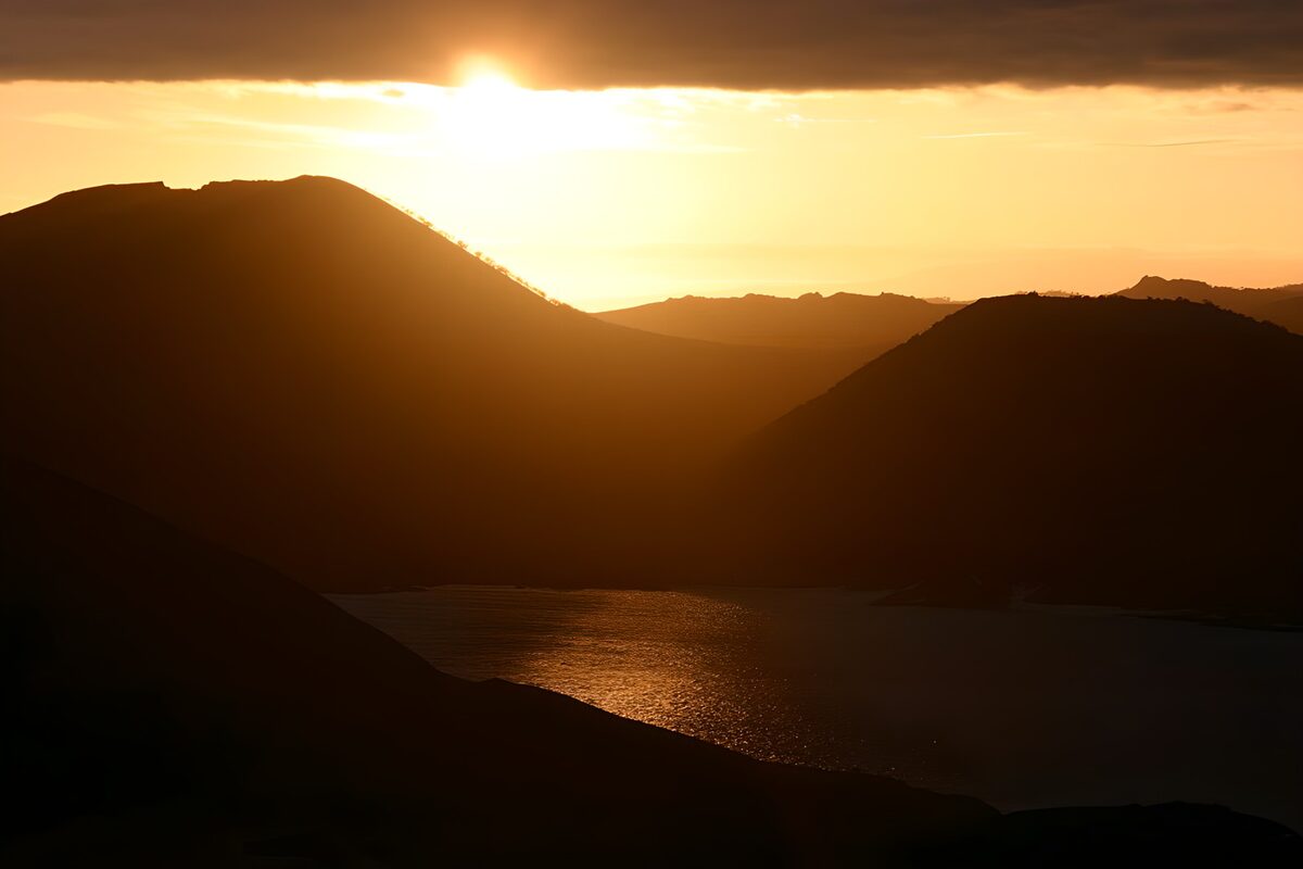 Sole basso sull’acqua tra montagne in ombra