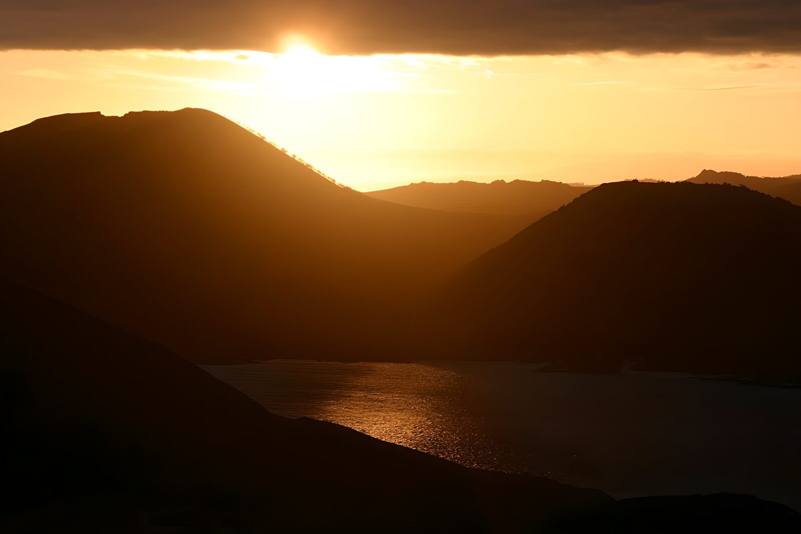 PDGIT1951208: Sole basso sull’acqua tra montagne in ombra