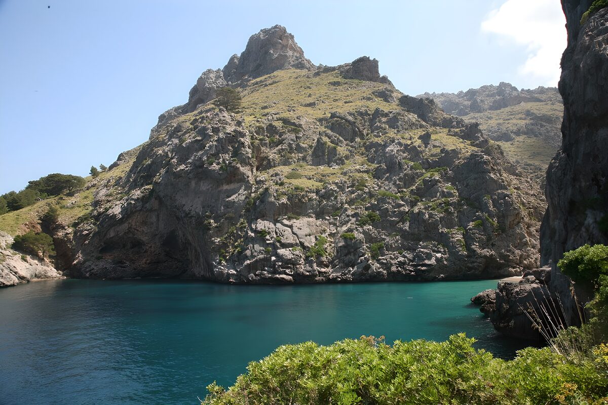 PDGIT4918275: Acqua turchese tra scogliere e arbusti