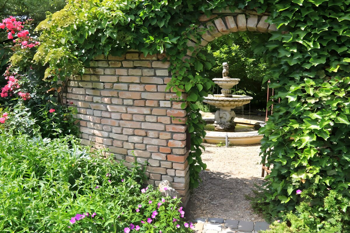 PDGIT1729552: Arco di edera e fontana in giardino
