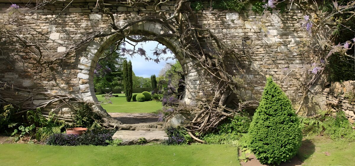 PDGIT5480683: Arco in pietra tra prato e fiori viola