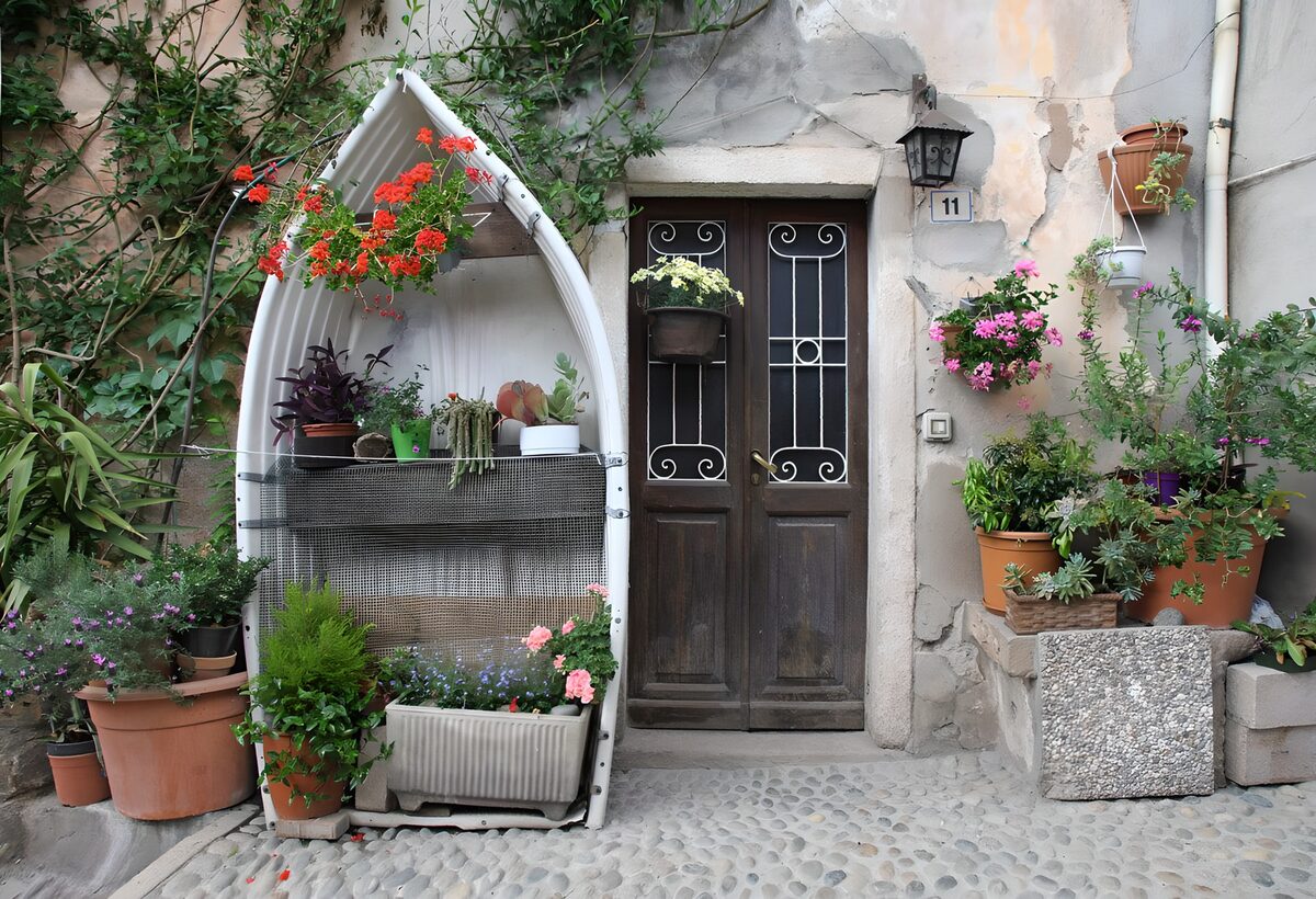 PDGIT3470178: Porta di legno tra vasi e muri rustici
