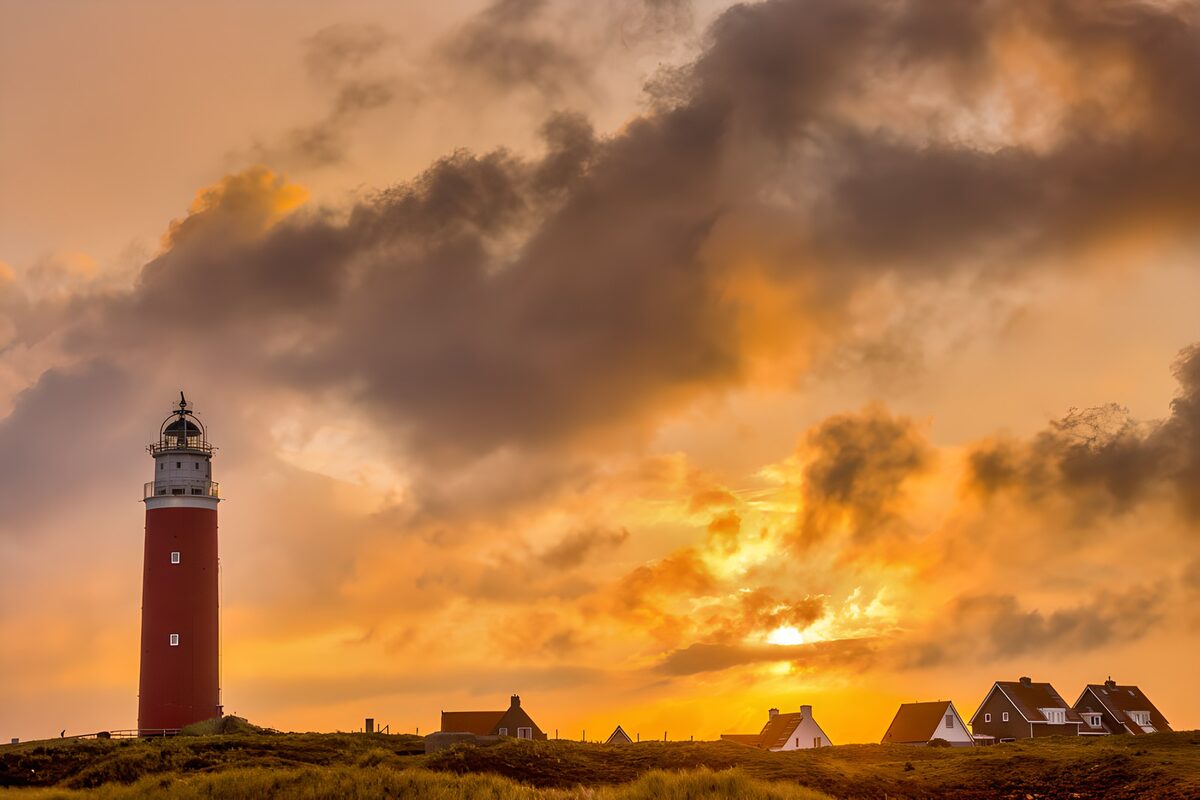 PDGIT9235167: Faro rosso e case al tramonto
