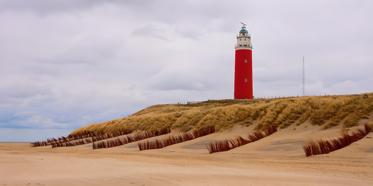 PDGIT2561155: Faro rosso tra dune e cielo grigio