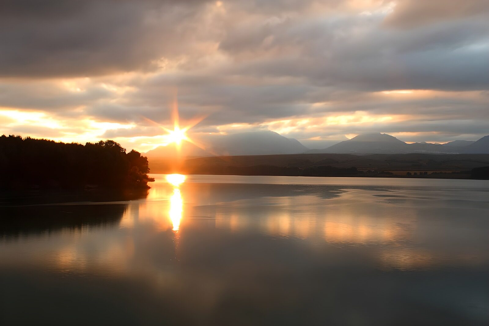 PDGIT1228423: Tramonto sul lago tra nuvole e montagne