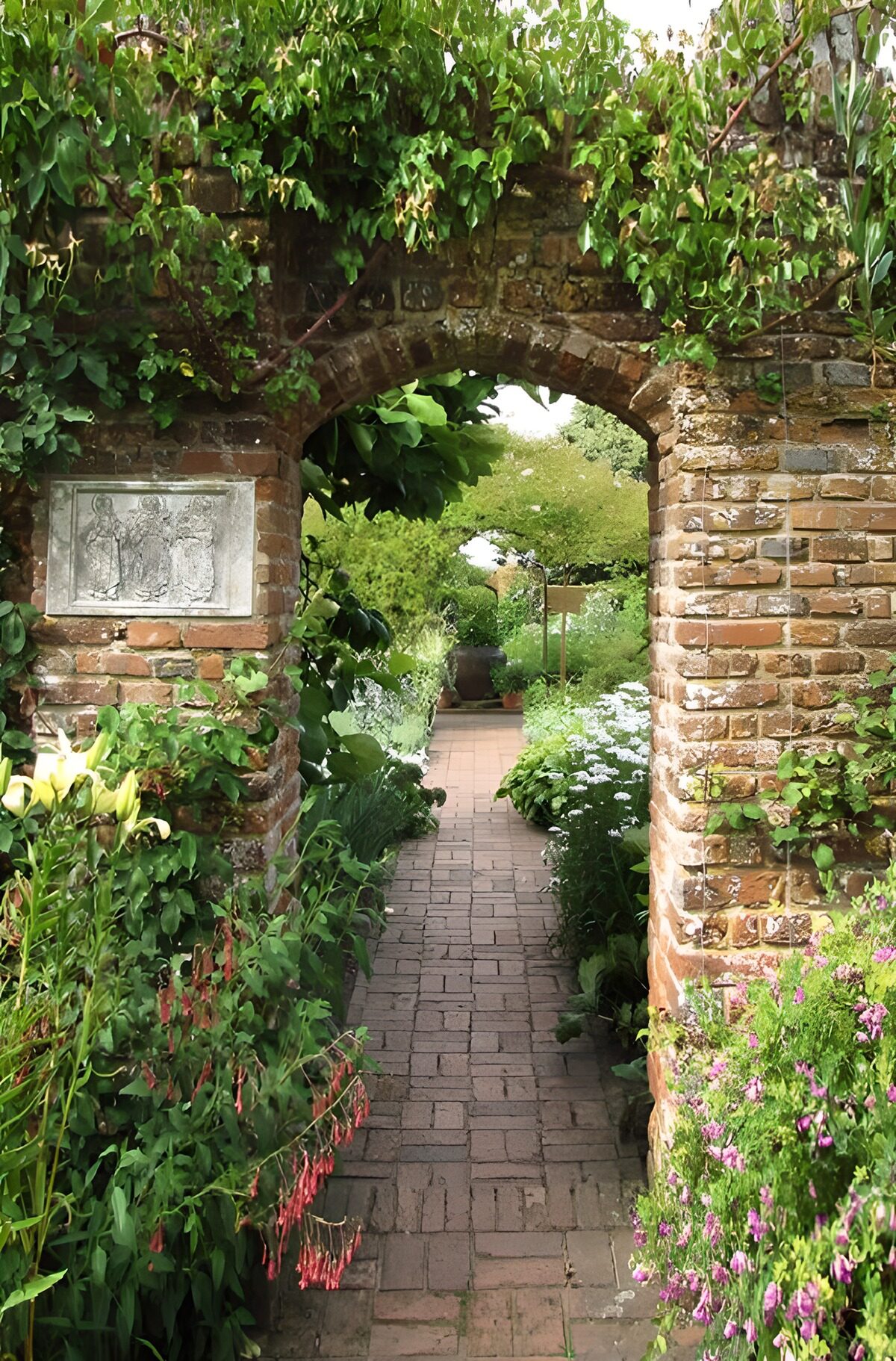 PDGIT7871357: Arco di mattoni tra fiori e ombra