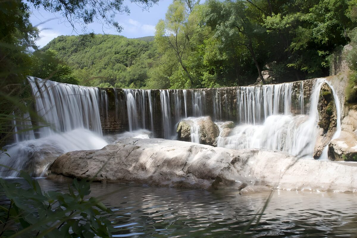 Cascata tra rocce e bosco d'estate
