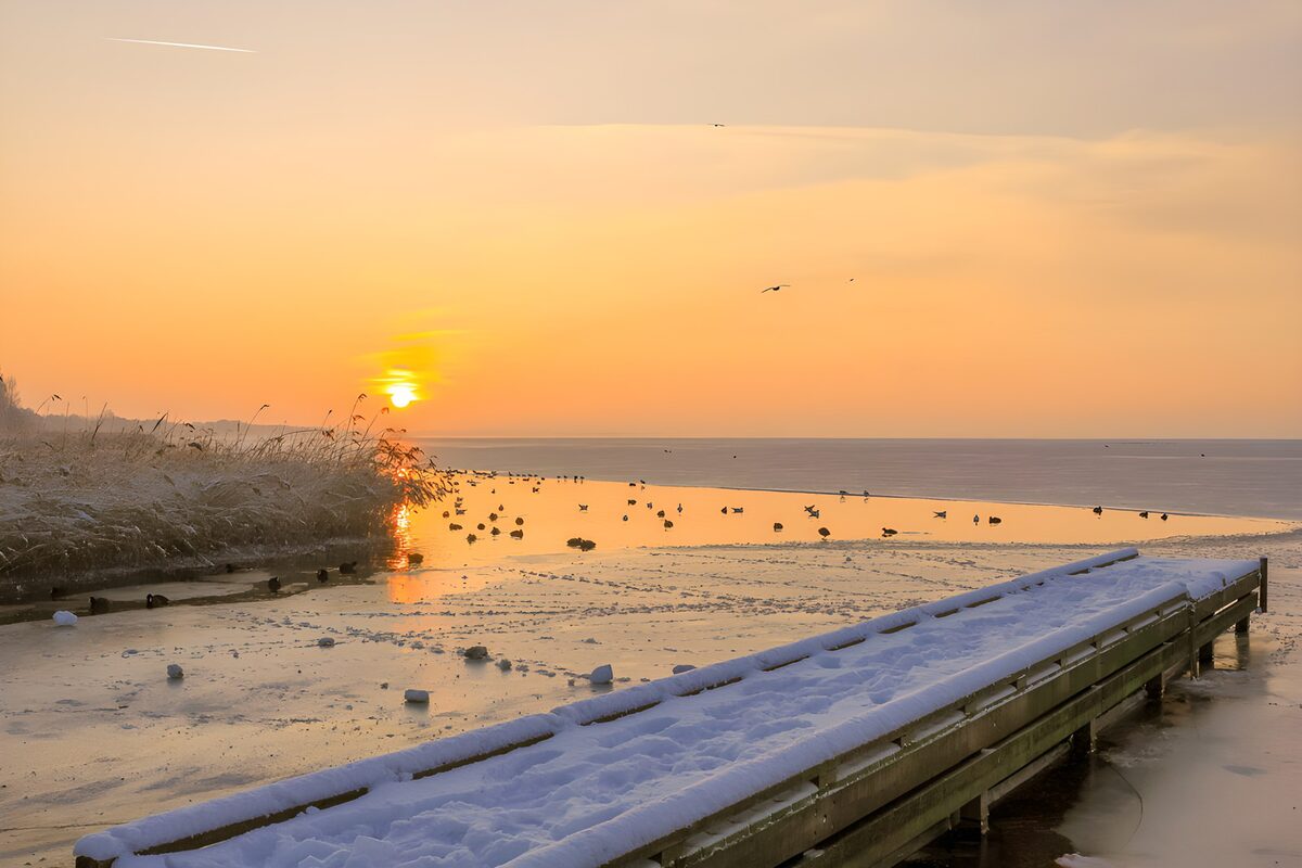 Pontile innevato sul lago al tramonto