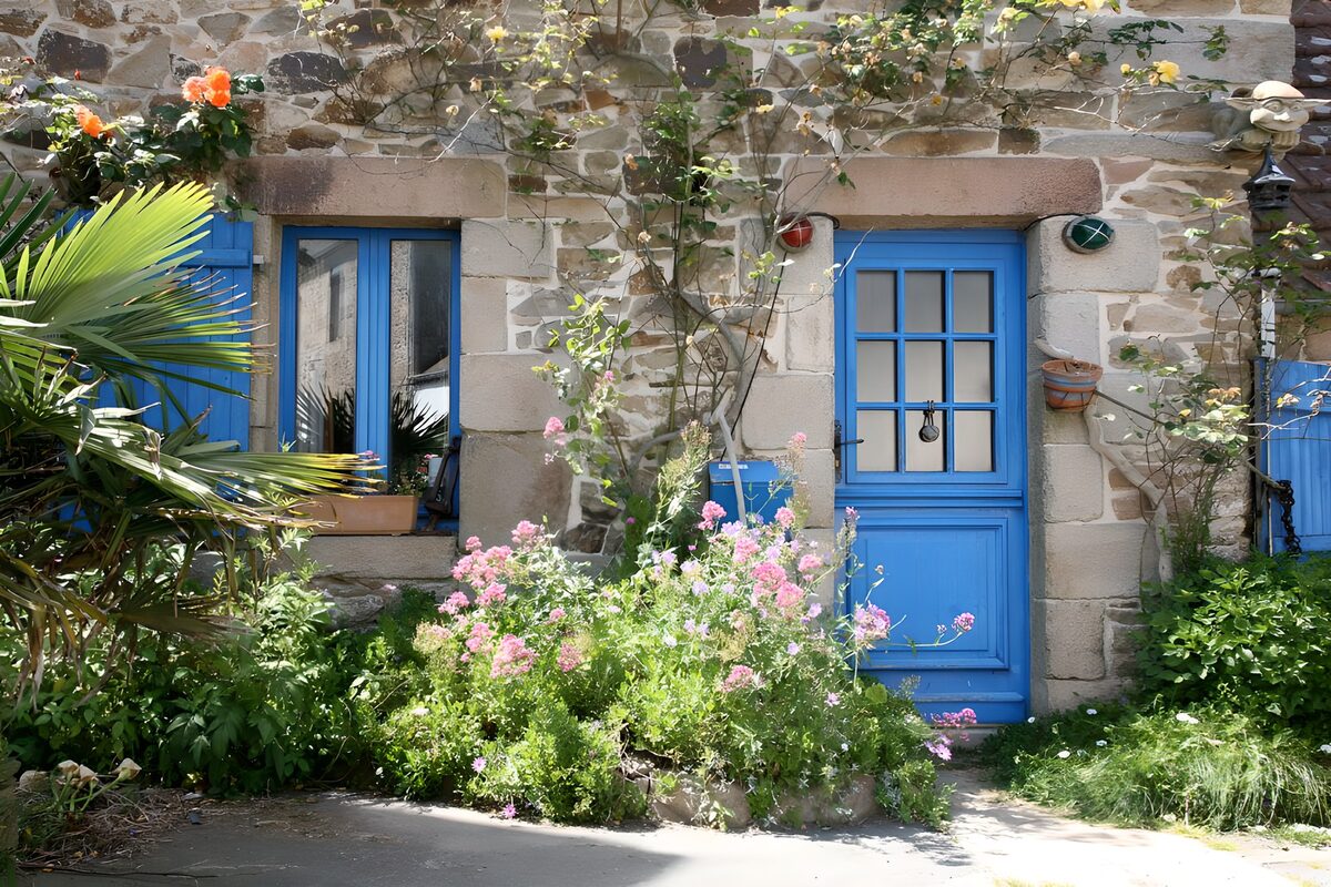 PDGIT3394254: Casa rustica con porta blu e fiori rosa