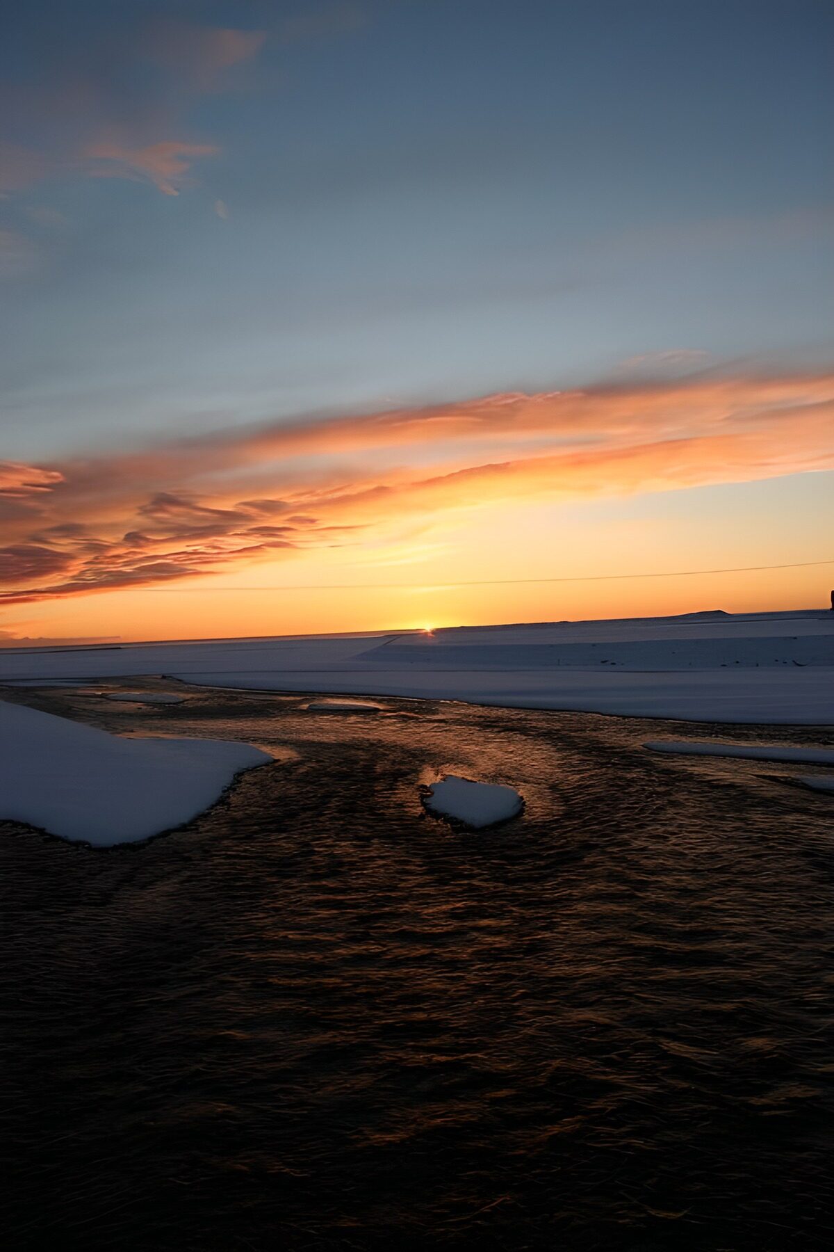 PDGIT8567872: Acqua e neve sotto il cielo arancio