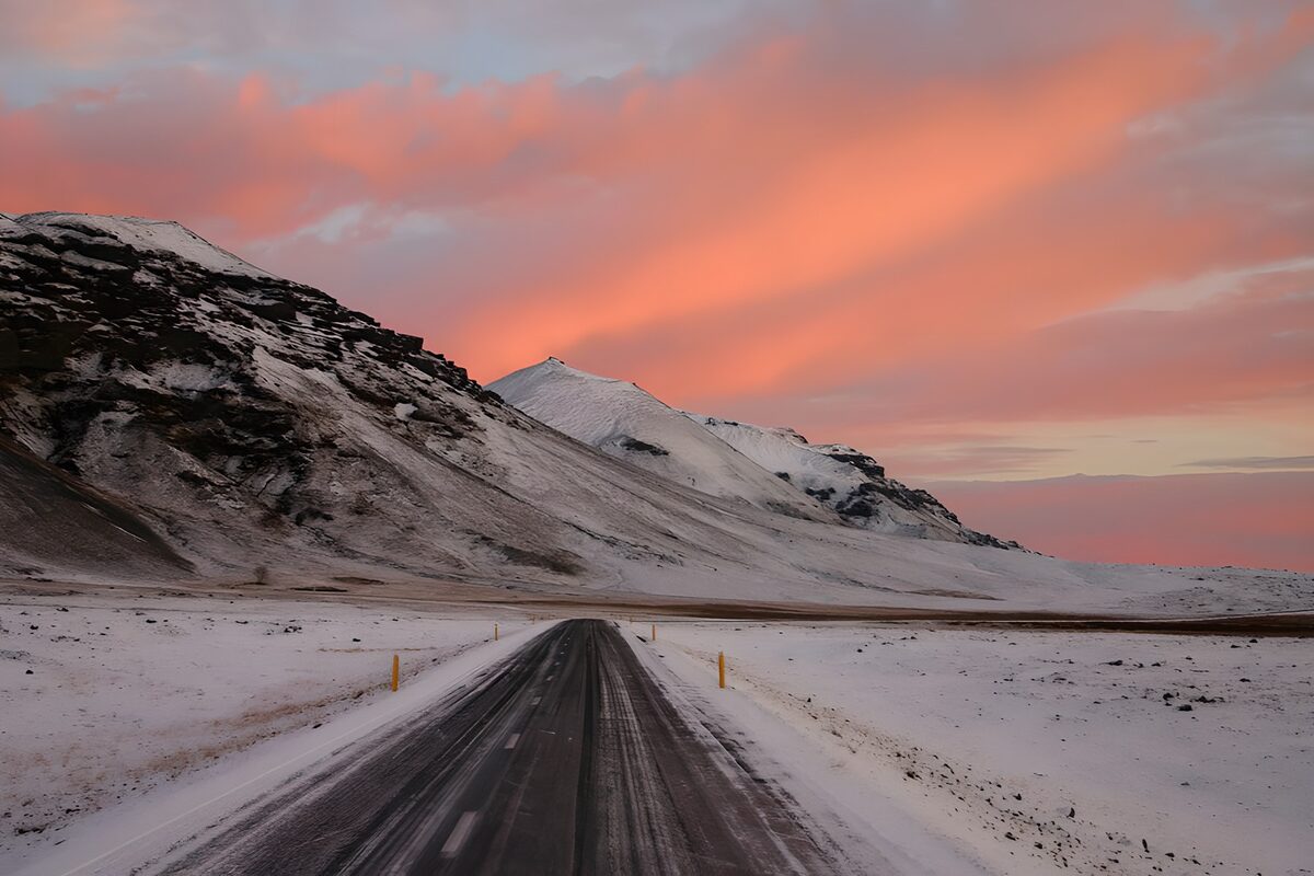 Strada innevata sotto un cielo rosa