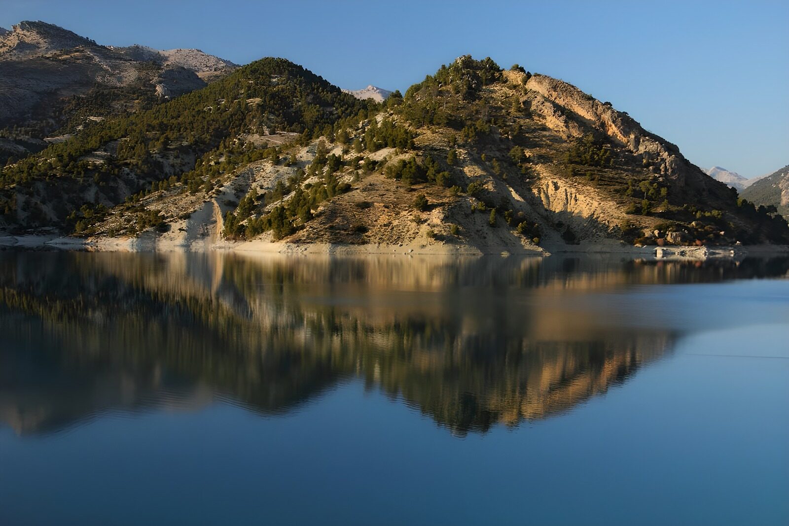 PDGIT7593626: Lago calmo tra rocce e boschi